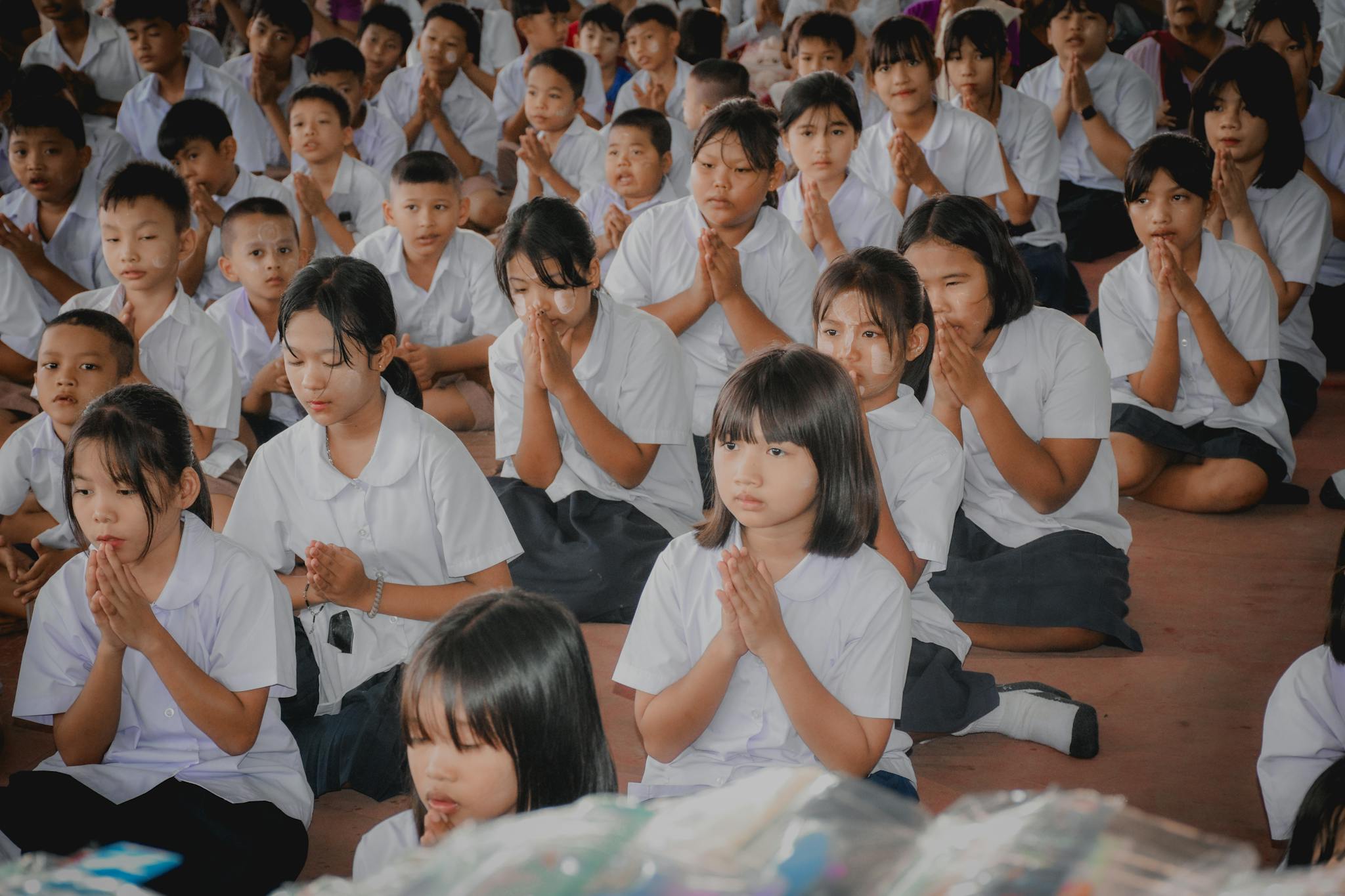 Students in uniform meditating at a school assembly, focused and serene.